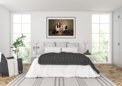 Bedroom scene with a photograph of a family of 4 hanging above a bed Wirral family Photographer