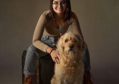 Smiling teenager sitting with her labradoodle dog wirral children's photographer