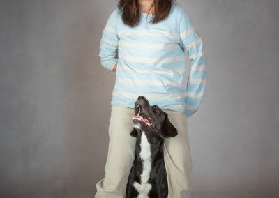 Young girl standing feet apart smiling whilst her dog looks up adoringly at her. Wirral family photographer