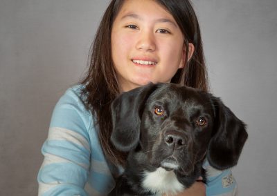 Young girl holding her puppy and smiling in a warm embrace Wirral children's photographer