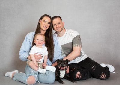 Mum and dad , little boy and black french bulldog smiling and sitting on the floor Wirral family photographer