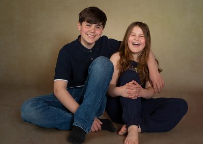 Brother and sister both laughing sitting on the floor North Wales Childrens photographer